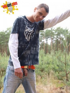 The boy in blue jeans standing in the forest and wants to pee